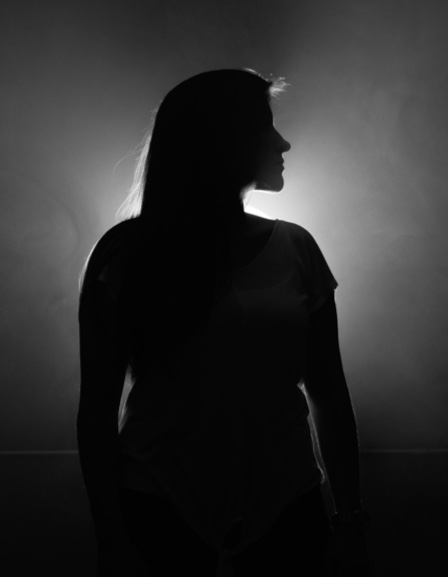 black and white photo of a woman standing in the light